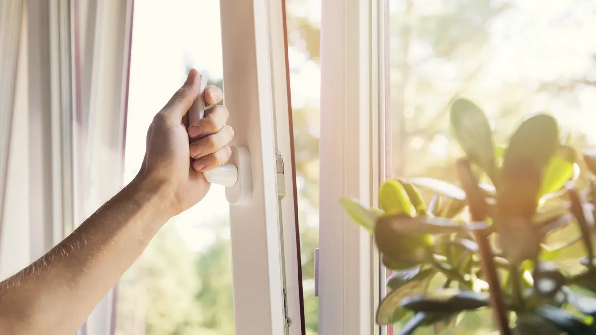 Eine Hand öffnet ein Fenster.