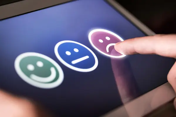 Auf einem Tablet drückt jemand auf einen unzufriedenen Smiley