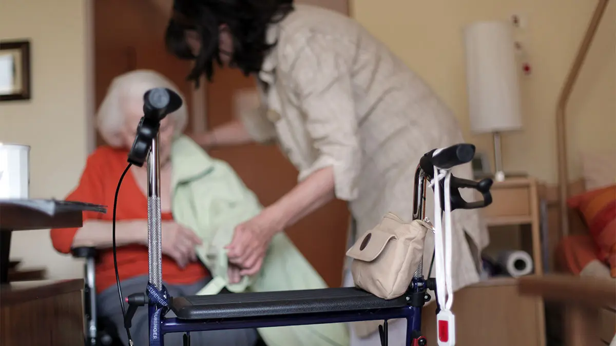 Rollator steht vor Seniorin und Pflegerin