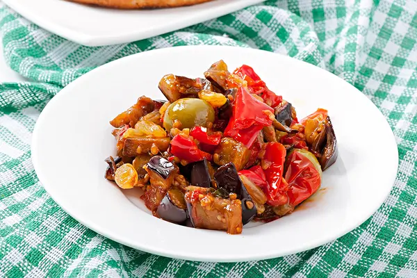 Caponata aus Aubergine, Paprika und Oliven auf einem Teller