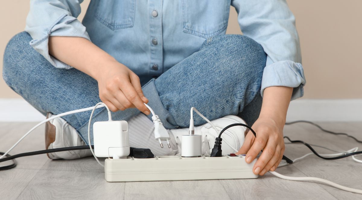 Jemand zieht einen Stecker aus einer Steckerleiste 