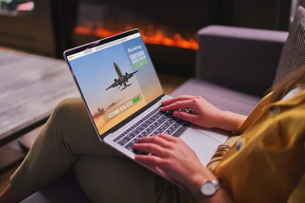 Eine Person sitzt an einem Laptop auf dem ein Flugzeug zu sehen ist. 