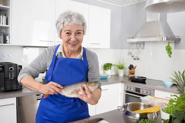 Eine Dame bereitet in der Küche Fischgericht vor
