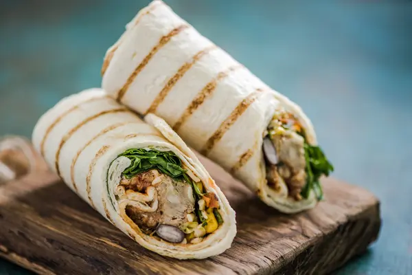 zwei Wraps mit Füllung auf einem Holztablette 