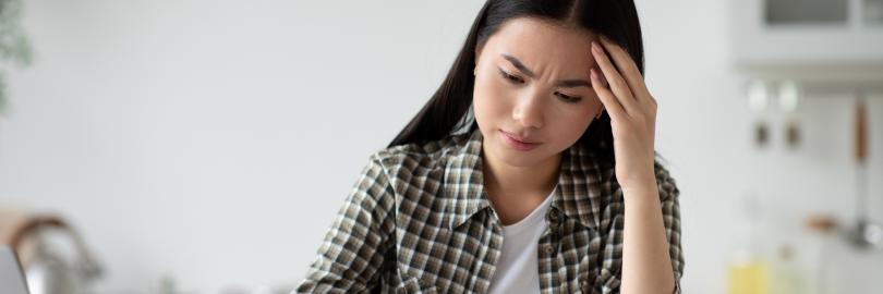 Eine Frau sitzt am Küchentisch mit einem Brief. Ihr Blick ist zweifelnd. 
