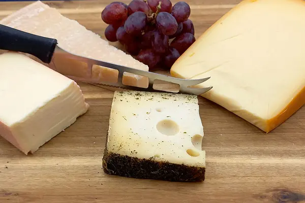 Verschiedene Käse am Stück liegen auf einem Holzbrett.