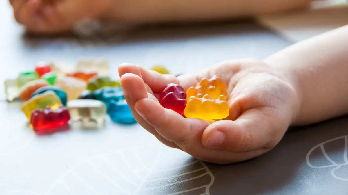 Ein paar Gummibärchen liegen in der Hand eines Kindes.