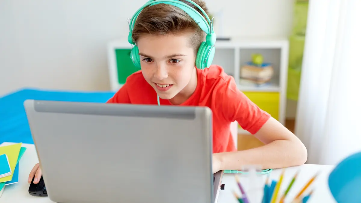 Junge sitzt vor dem Laptop und hat Kopfhörer auf