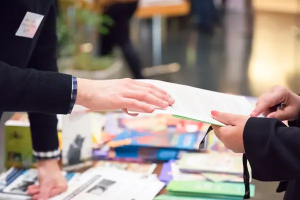 An einem Infostand wird ein Vertrag zwischen zwei Menschen besprochen