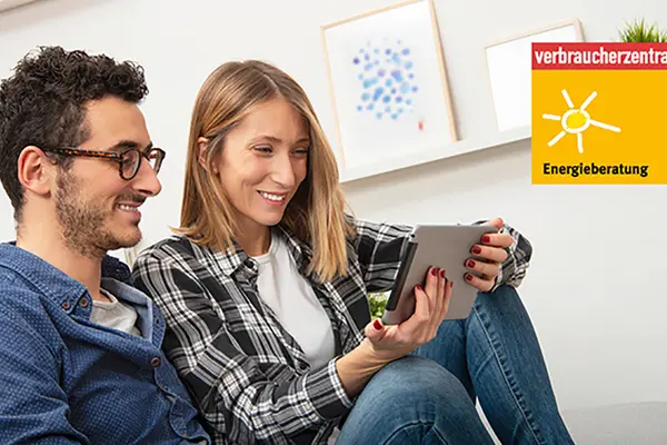 Ein Paar sitzt auf dem Sofa und informiert sich mit einem Tablet-PC