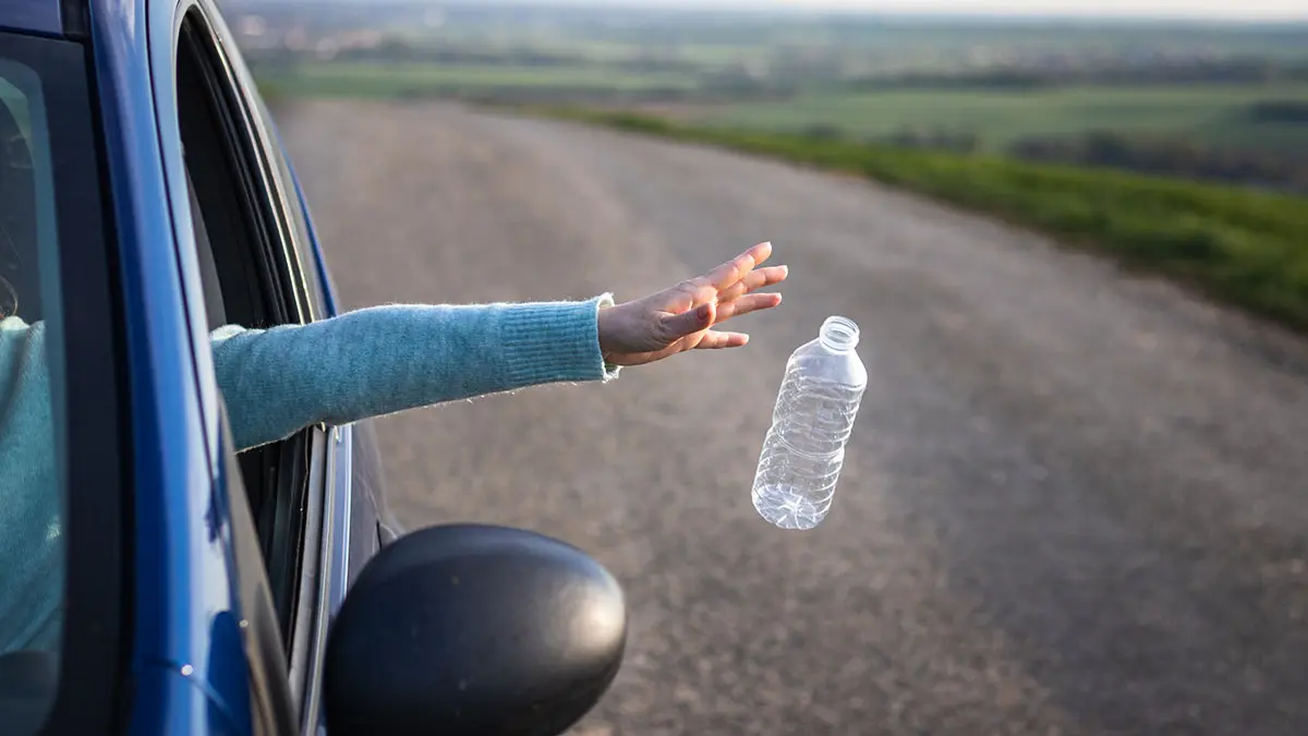 Jemand wirft eine Plastik-Trinkflasche aus dem Autofenster