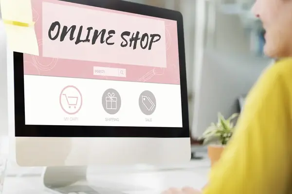 Eine Person sitzt vor einem Bildschirm auf dem groß Online-Shop steht.