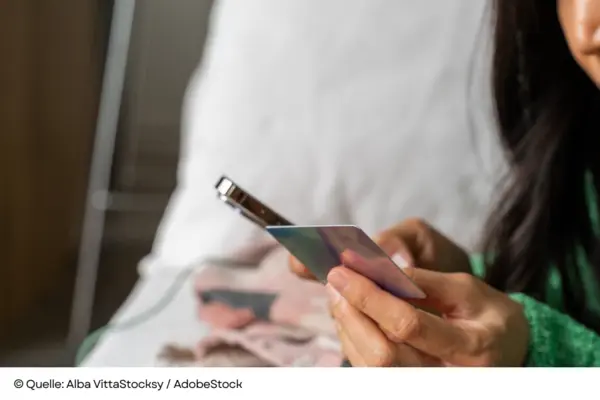 Nahaufnahme einer Frau, die beim Online-Shopping eine schimmernde Zahlungskarte und ein Smartphone benutzt.