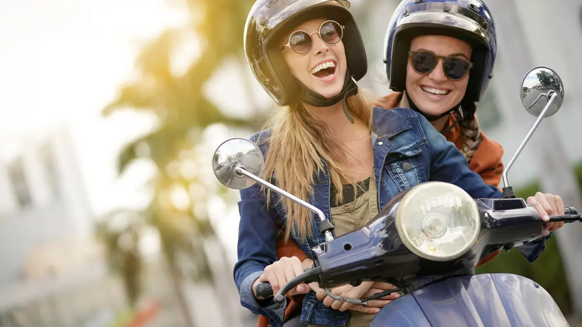 Zwei Frauen lachen auf dem Roller