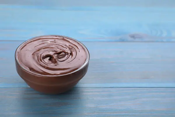 Eine Schüssel Schokopudding steht auf einem blauen Holztisch