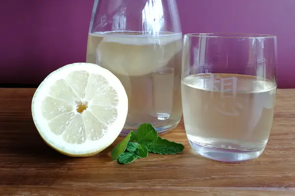 Gefüllte Karaffe und Trinkglas mit angeschnittener Zitrone