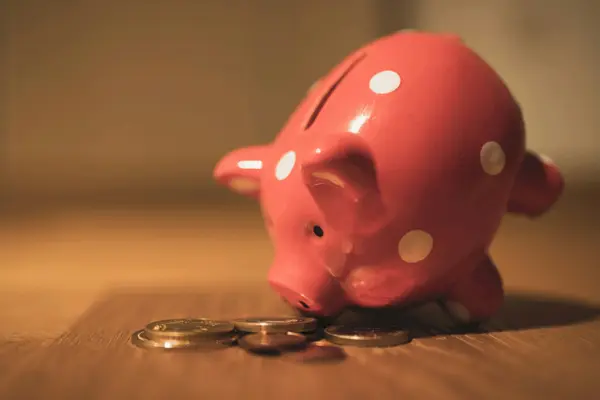 Sparschwein mit Münzen auf Holztisch