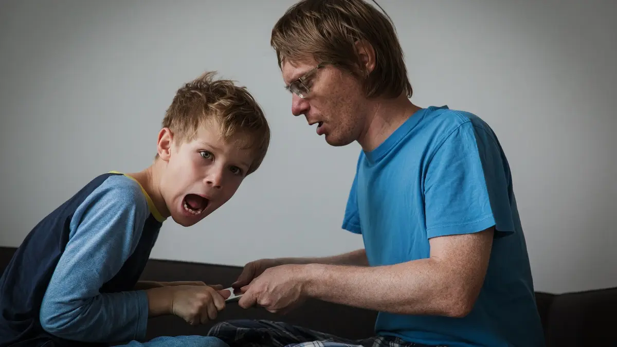 Vater und Sohn streiten sich um ein Tablet. Der Vater will es dem Sohn wegnehmen, der das nicht will.