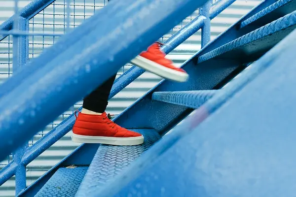 Person mit roten Schuhen läuft blaue Treppe hich