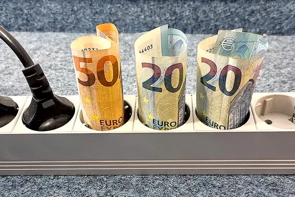 Geldscheine (50 und 20 Euro) stecken aufgerollt in drei Fächern einer Stromsteckerleiste