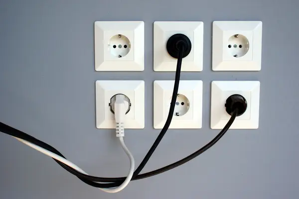 Mehrere Steckdosen in der Wand, teils mit Steckern
