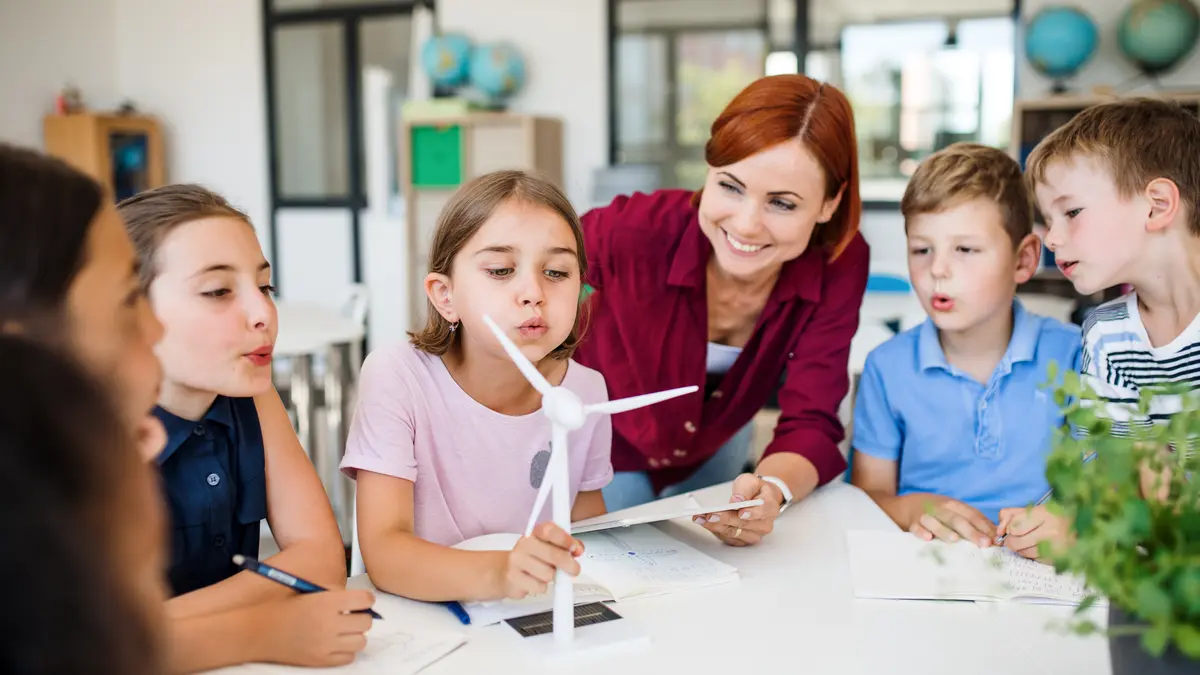 Lehrerin beim Erklären einer Windkraftanlage mit einer Gruppe Kinder