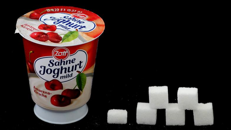 Joghurtbecher von Zott und daneben eine Zuckerwürfel-Pyramide