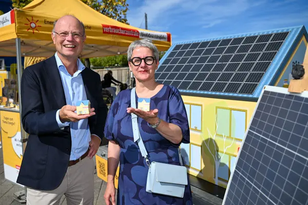 Silke Krebs, Staatssekretärin im Ministerium für Wirtschaft, Industrie, Klimaschutz und Energie des Landes Nordrhein-Westfalen und Wolfgang Schuldzinski, Vorstand der Verbraucherzentrale NRW zeigen kleine Modelle eines Hauses mit einem Stand der Verbraucherzentrale im Hintergrund