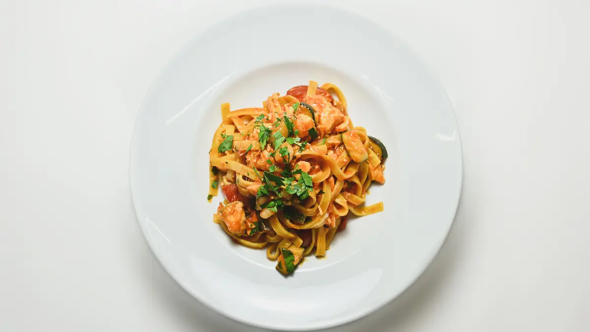 Nudeln mit Zucchini Tomatensauce auf einem weißen Teller