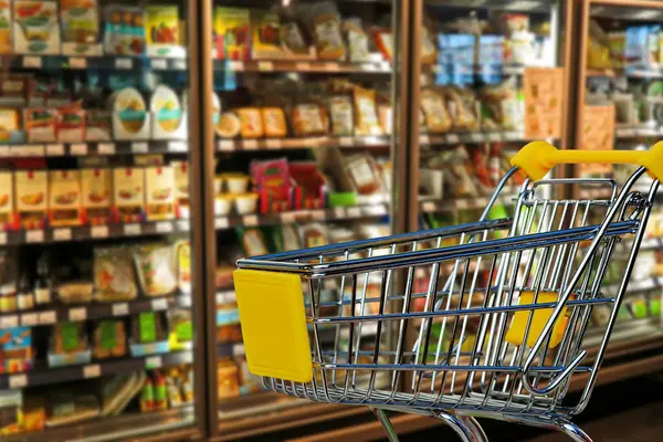 Leerer Einkaufswagen vor Supermarkt-Kühlschränken