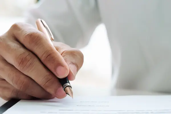 Eine Hand unterzeichnet ein Schriftstück