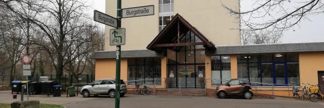 Auf dem Foto ist der Haupteingang der Josephinen-Wohnanlage abgebildet. Davor ist das Straßenschild mit der Aufschrift Burgstraße zu sehen.