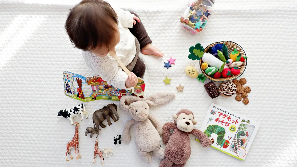 Kind sitzt inmitten von Spielzeug