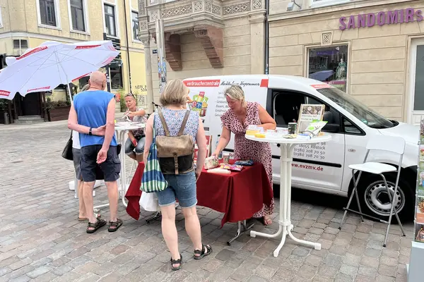 das Auto der Verbraucherzentrale mit einem Infostand davor, vor dem stand stehen Menschen