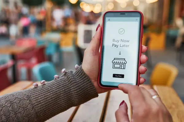 Ein Smartphone wird in den Händen gehalten. Auf dem Display steht Buy now, pay later