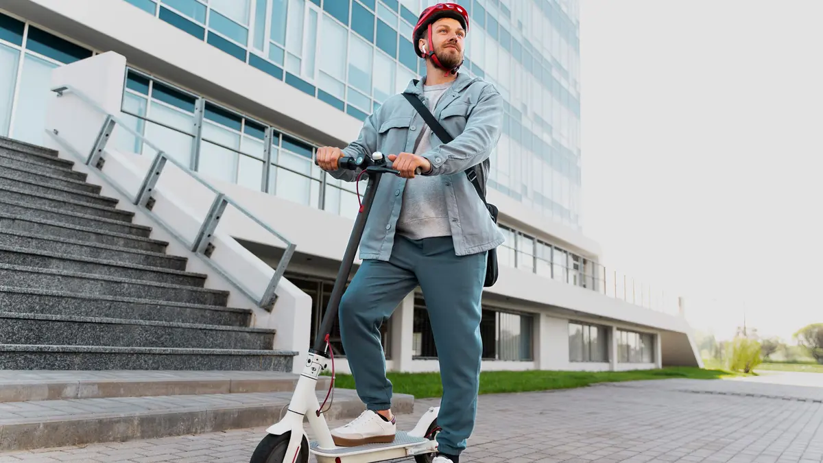 Ein Mann steht mit einem E-Scooter vor einem Bürogebäude
