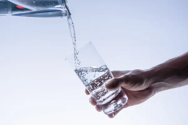 Glas Wasser wird aus Karaffe gefüllt