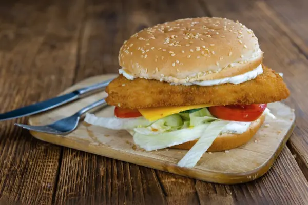 Ein Burgerbrötchen mit Fisch, Soße und Salat