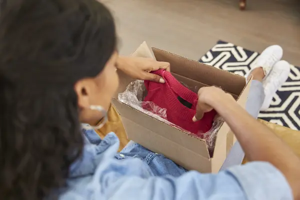 Frau packt ein Paket mit online bestellter Kleidung aus