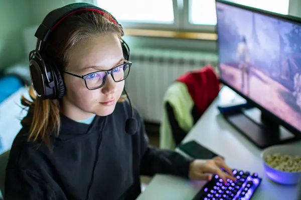Ein Mädchen mit Kopfhören sitzt am PC beim Gaming
