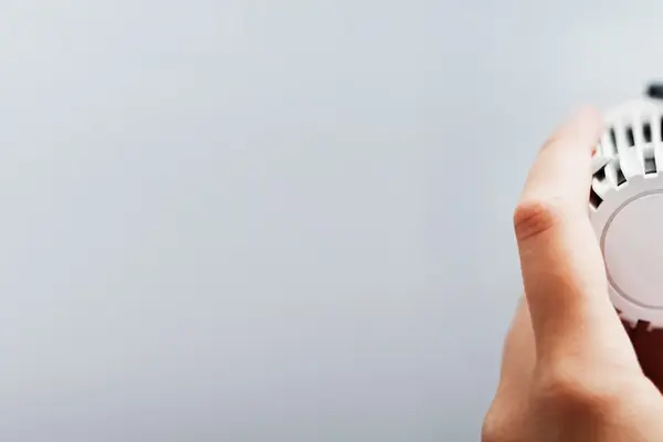 Eine Hand dreht an einem Heizkörperthermostat