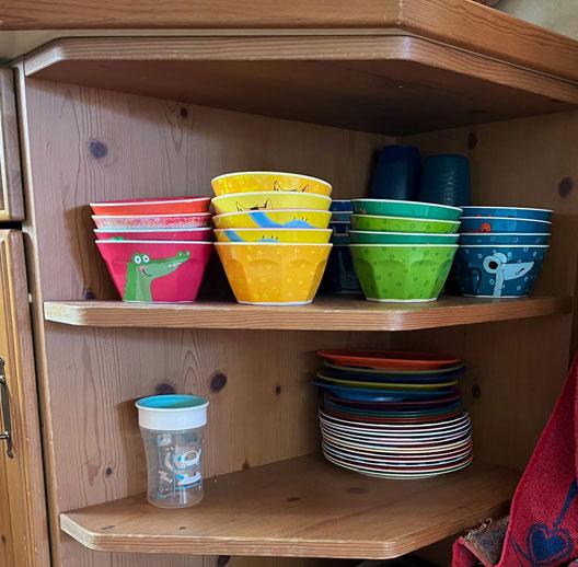 In einem bodennahen Regal steht Kindergeschirr