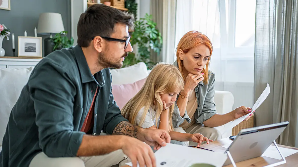 Eine Familie sitzt auf dem Sofa und studiert Unterlagen