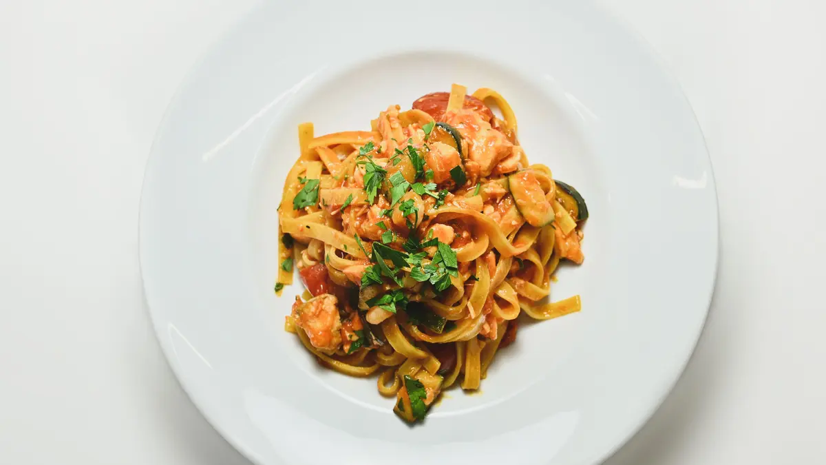 Nudeln mit Zucchini Tomatensauce auf einem weißen Teller
