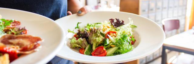 Eine Frau hält zwei Teller mit Salat