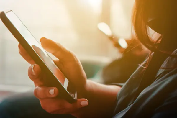 eine Person sitzt auf dem Sofa und blick auf das Smartphone in ihrer Hand 