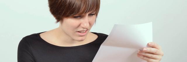 Frau blickt entsetzt auf Brief