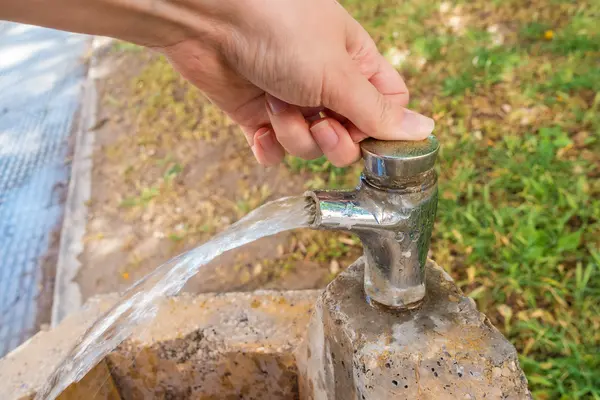 Frau bedient einen Trinkwasserbrunnen