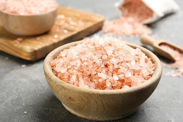 Eine Holzschüssel mit rotem Hawaii-Salz steht auf einer schwarzen Arbeitsfläche.
