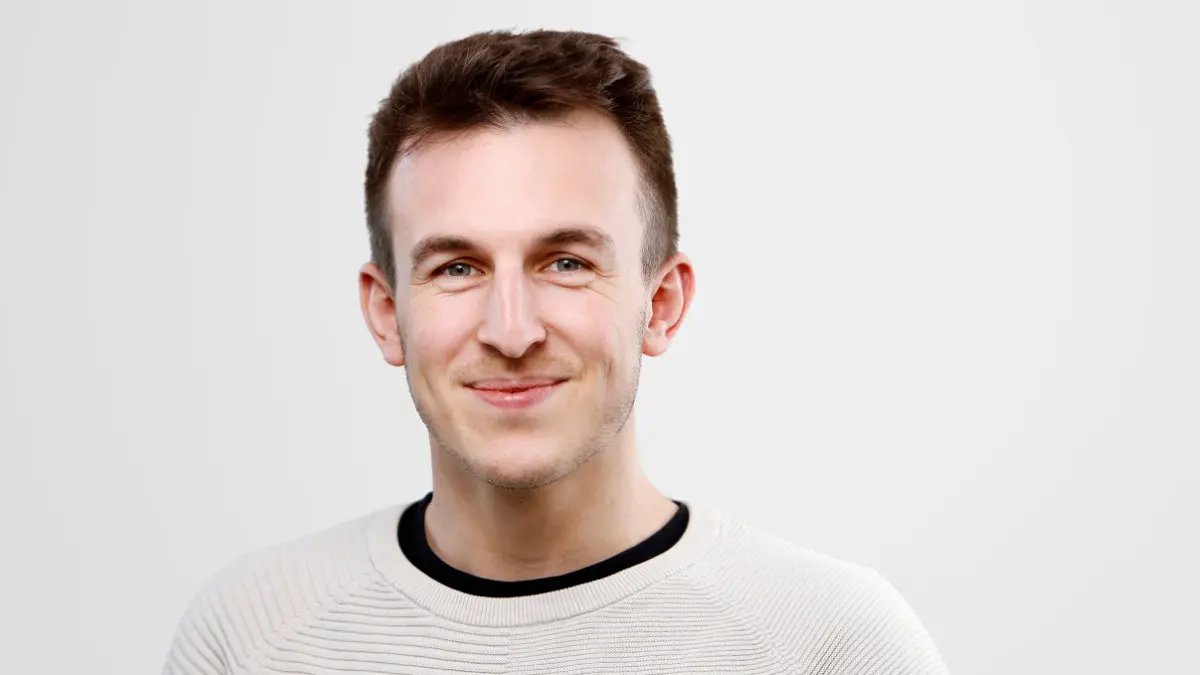Ein Mann mit kurzen dunklen Haaren lächelt in die Kamera